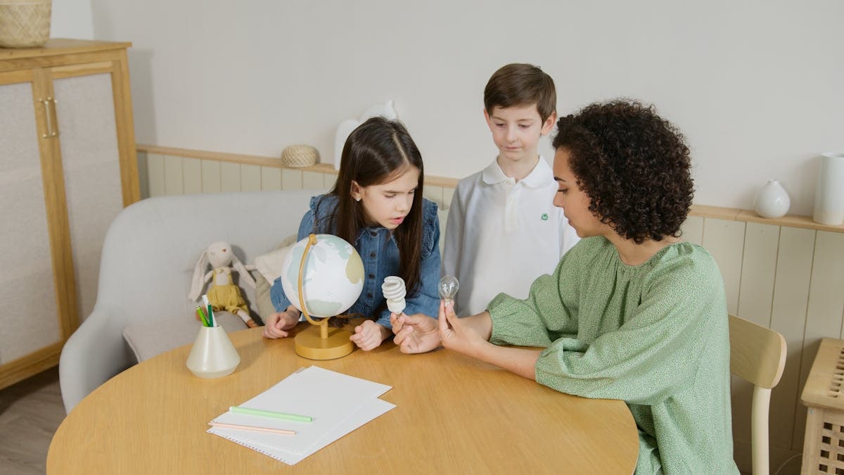 Mother teaching children about light bulbs and energy with a globe at home.